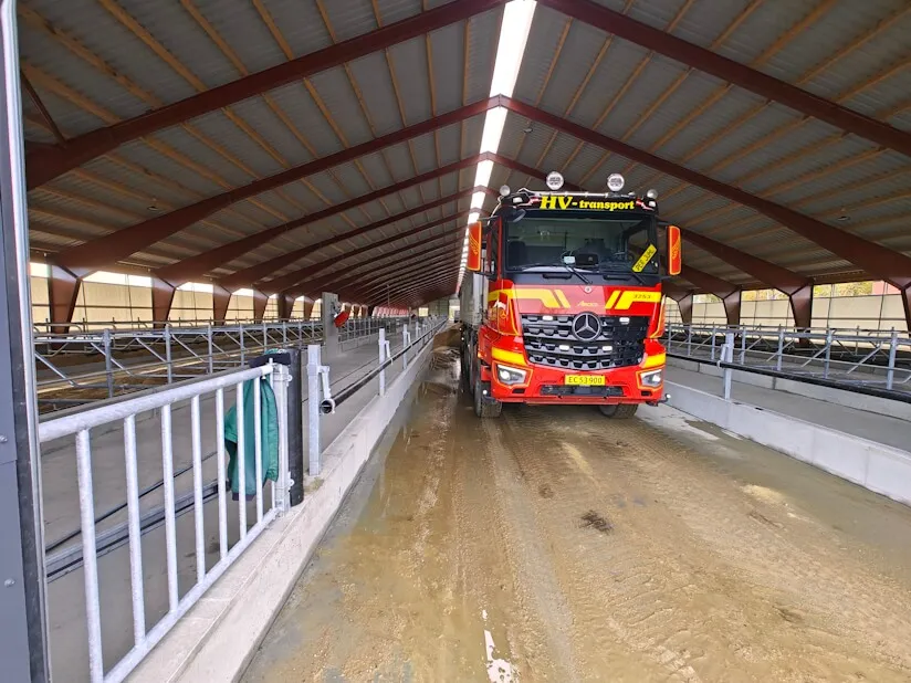 Lastbil aflæsser sand til sengebåse i ko-stalden