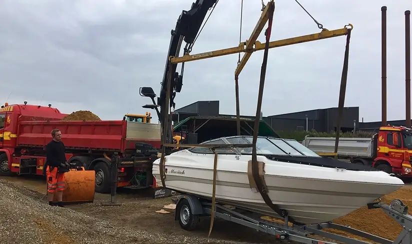 En mindre båd bliver løftet med en kran