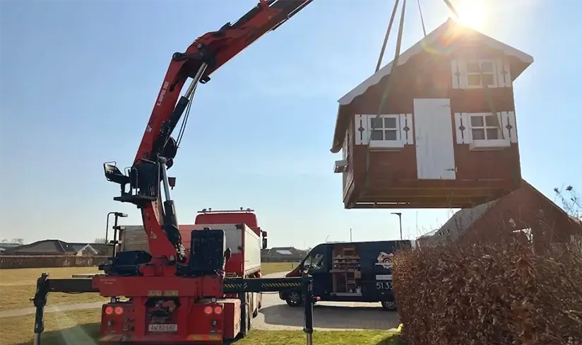 Stort legehus bliver flyttet til en ny lokation ved hjælp af en kran.