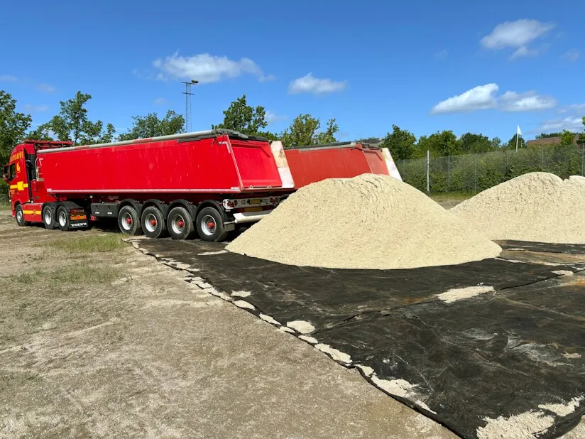 To lastbiler der leverer strandsand til en kunde