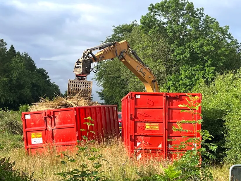 En kran der fylder haveaffald over i containere fra HV-transport.